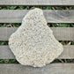 Large beige stone on a wooden surface with grass in the background