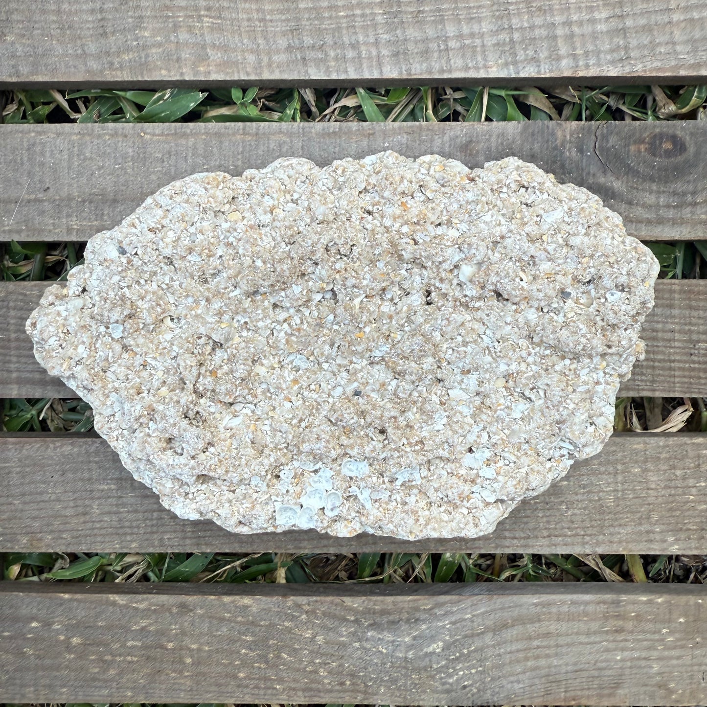 Large stone on a wooden surface with grass in the background