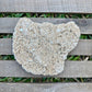 Heart-shaped stone on a wooden surface with grass in the background